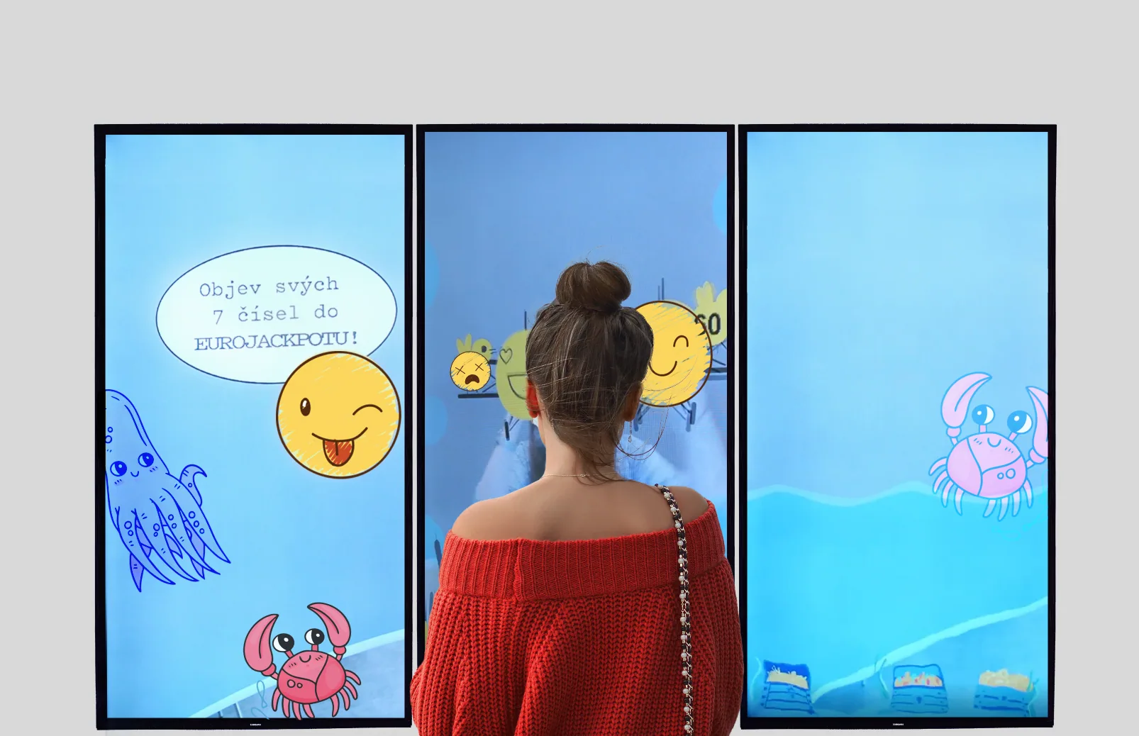 A visitor standing before three tall screens showing an illustrated underwater game — a squid, crabs and winking smiley faces — inviting her to find seven Eurojackpot numbers.